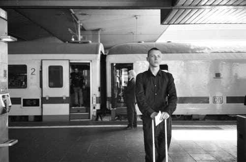站在火车旁边的人的单色照片 · 免费素材图片