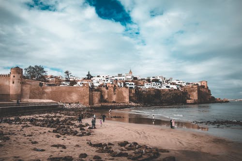海边的人，被坚固的城墙包围的一个村庄附近 · 免费素材图片