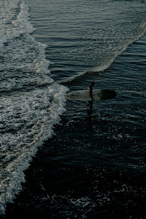 男子携带冲浪板的照片 · 免费素材图片