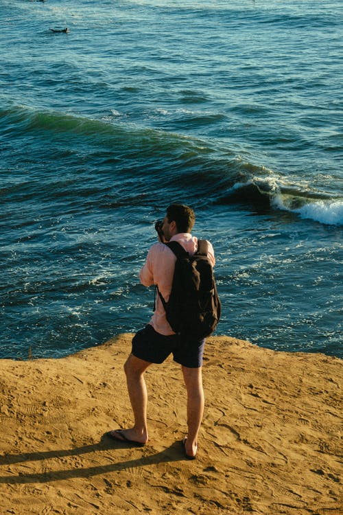 站在蓝色的海洋旁边的人 · 免费素材图片