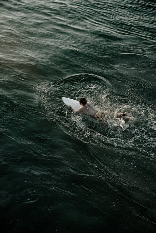 男子骑在水面上的白色冲浪板 · 免费素材图片