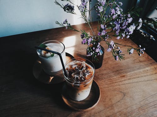 在桌子上的花旁边的两个清晰的水杯 · 免费素材图片