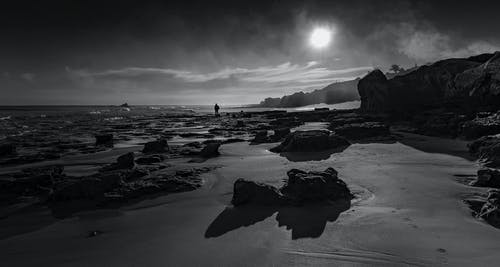 人站在海边剪影的灰度摄影 · 免费素材图片