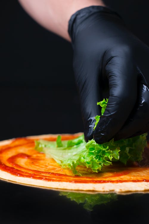 戴手套把生菜放在披萨上的人 · 免费素材图片