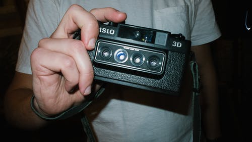 拿着黑色尼姆斯洛相机的人 · 免费素材图片