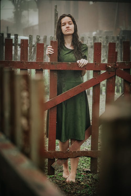 绿色顶站在栅栏上的女人 · 免费素材图片