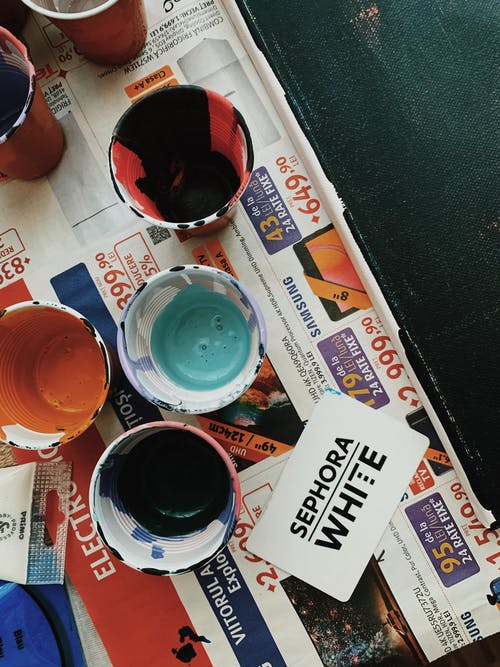 杯子用报纸上的各种颜色的油漆 · 免费素材图片