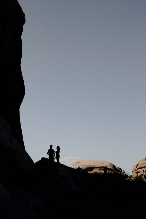 两人站在岩石上的剪影 · 免费素材图片