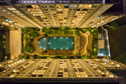 高层建筑之间的矩形绿色游泳池的高角度摄影 · 免费素材图片