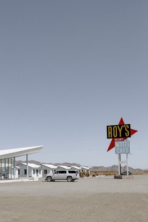 白色的车停在罗伊的标牌附近 · 免费素材图片