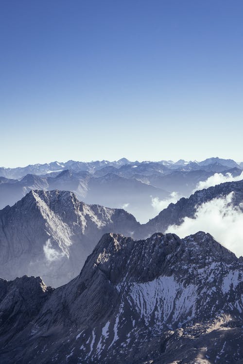 在蓝色和白色的天空下白雪覆盖的山的航拍 · 免费素材图片