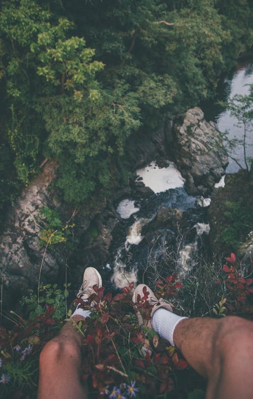 坐在山与花的边缘上的人 · 免费素材图片