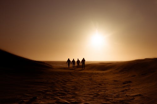 在沙丘上行走的人的剪影 · 免费素材图片