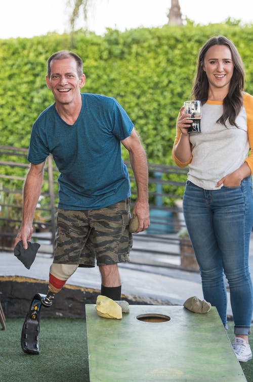 男人在旁边喝一杯的女人旁边玩玉米坑 · 免费素材图片