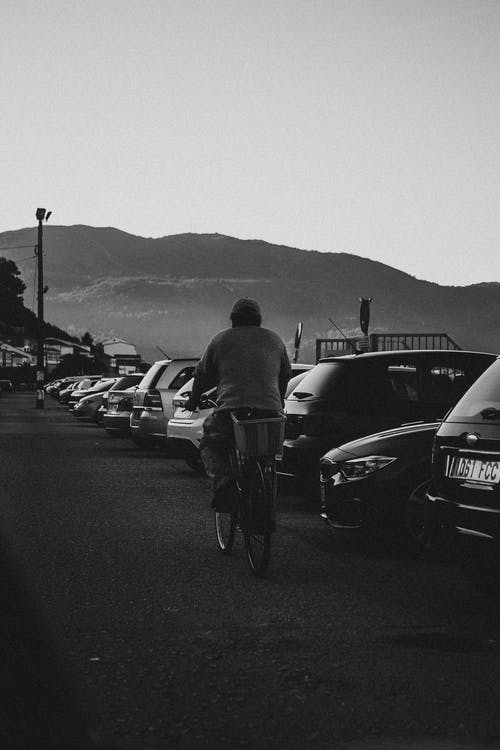 一名男子骑着自行车的灰度照片 · 免费素材图片