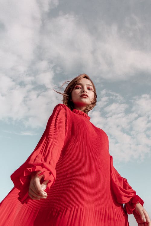 红色长袖连衣裙摆姿势的女人的低角度照片 · 免费素材图片