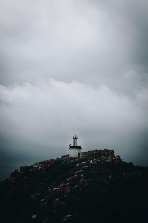 在灰色的天空下的一座山上的灯塔 · 免费素材图片