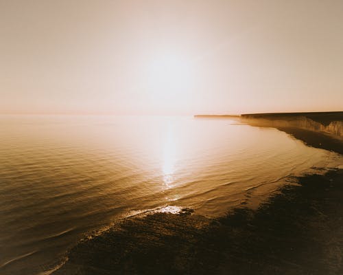 阳光照耀着大海的平静水域及其周围的风景 · 免费素材图片