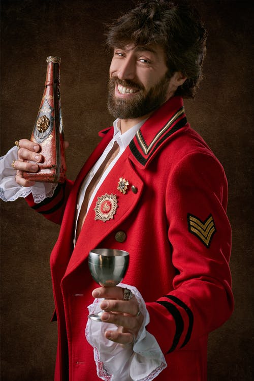 身穿红色和黑色军事套装，手持灰色钢长笛玻璃的男人 · 免费素材图片