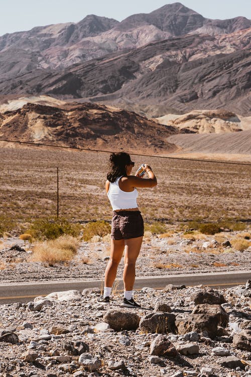 穿着短裤站在山附近的女人 · 免费素材图片