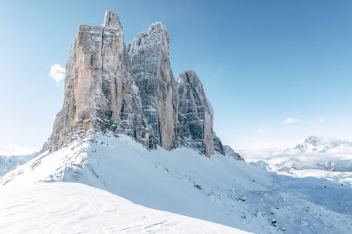 被白雪覆盖的地面包围的岩石山 · 免费素材图片