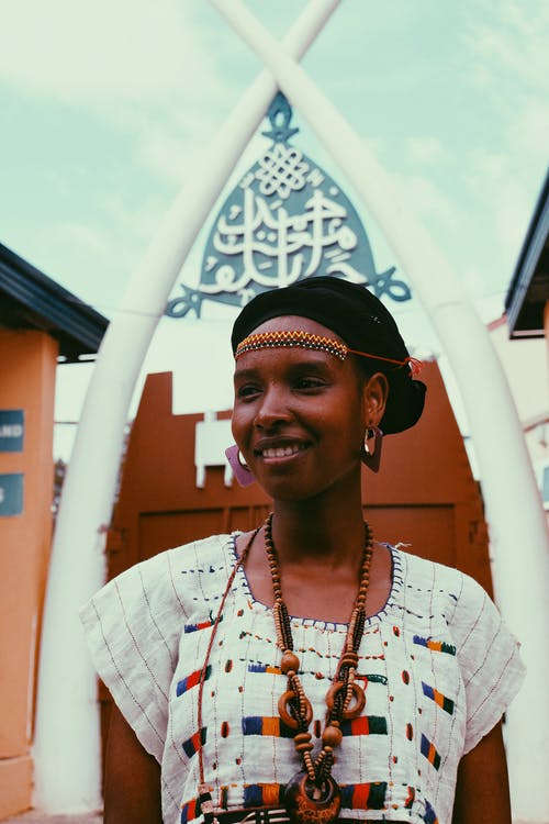 微笑的女人，在传统非洲服饰摆在视线时的照片 · 免费素材图片