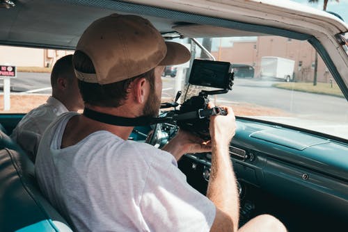 该名男子手持相机在车内的照片 · 免费素材图片