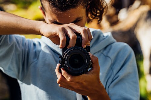 一个年轻人使用黑色的单反相机 · 免费素材图片