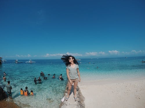 站在防波堤上的灰色衬衫的女人 · 免费素材图片