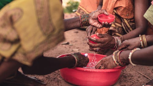 人们在一个圆形的红色塑料容器中洗手 · 免费素材图片