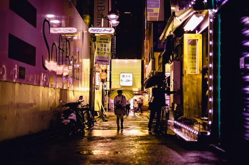 夜间行走在建筑物旁边道路附近的人 · 免费素材图片