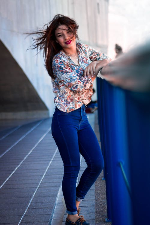 穿多彩多姿的花卉长袖上衣和蓝色牛仔裤的女人的照片 · 免费素材图片