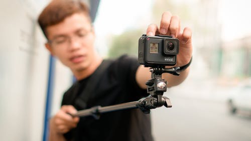 男子手持独脚架与行动相机 · 免费素材图片
