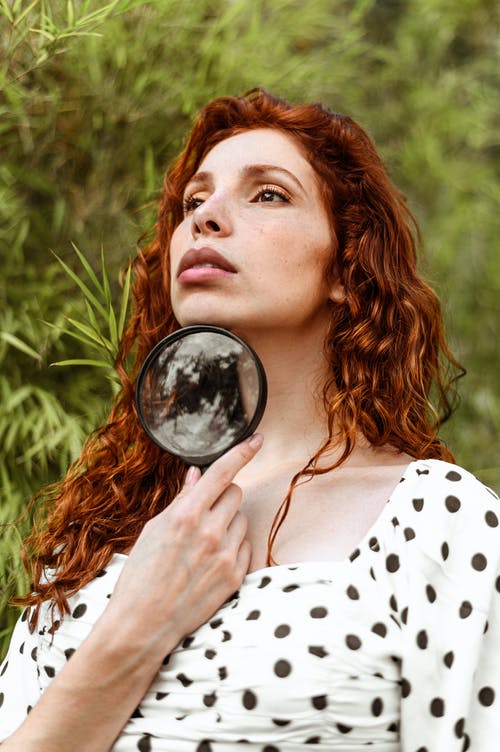 女人抱着黑框的放大镜 · 免费素材图片