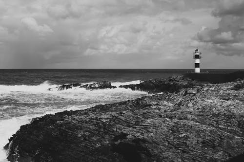 灯塔在海边的灰度照片 · 免费素材图片