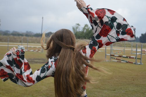 女人在花顶摆姿势与她的手的背影照片 · 免费素材图片