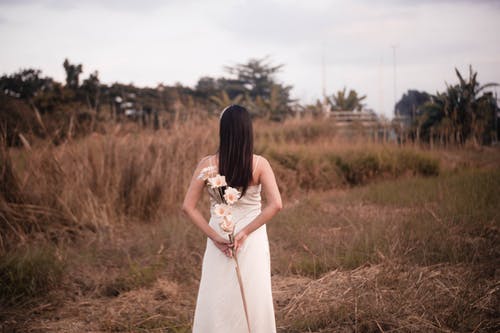 拿着花的白色礼服的妇女 · 免费素材图片