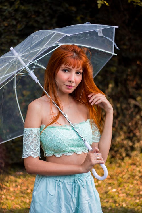 女人拿着透明的伞摆姿势的选择性焦点照片 · 免费素材图片