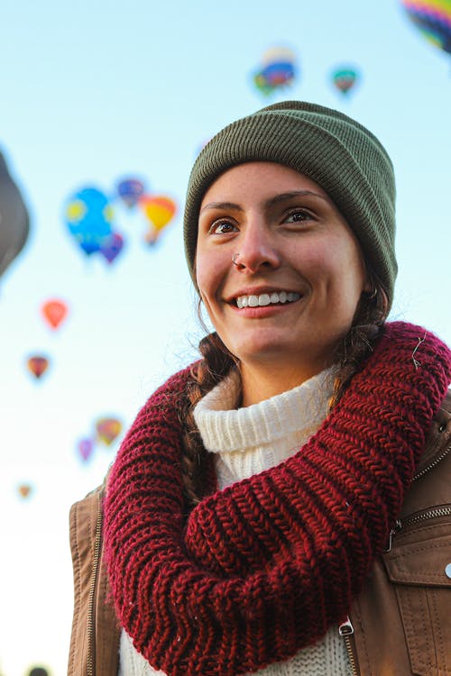 面带笑容的女人，穿着灰色豆豆帽和红色的围巾 · 免费素材图片
