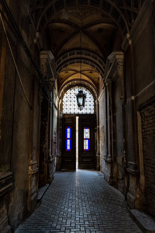 在老建筑的走廊尽头的黑色木制敞开的门的浅焦点照片 · 免费素材图片
