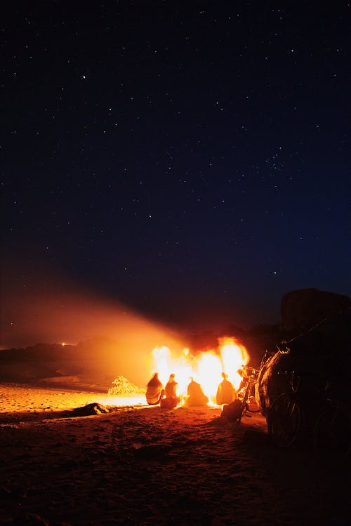 人们聚集在繁星点点的夜空下户外篝火旁 · 免费素材图片