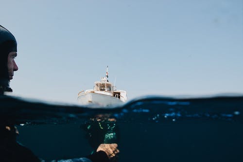 一艘游艇在海上和水下的人 · 免费素材图片