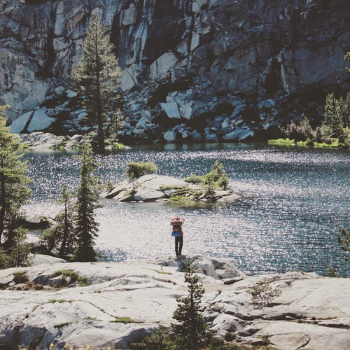站在一块岩石在水体附近的人 · 免费素材图片