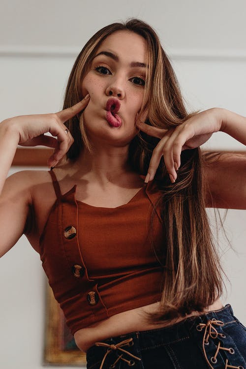 女人po着嘴唇，抚摸她的脸颊 · 免费素材图片