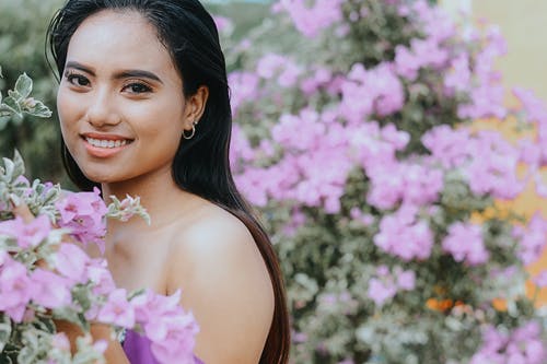 在粉红色的花朵旁边微笑的女人 · 免费素材图片