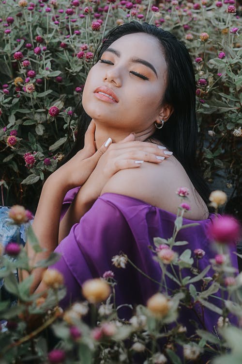 女人穿着露肩上衣被鲜花包围 · 免费素材图片