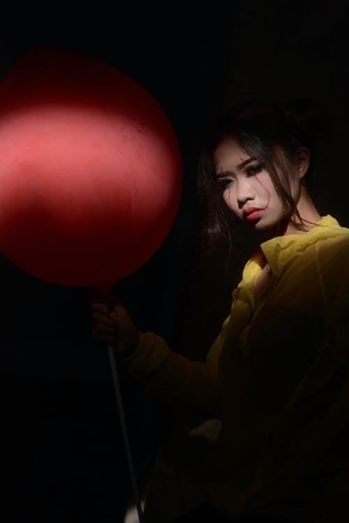 女人穿着黄色上衣拿着红色的气球 · 免费素材图片