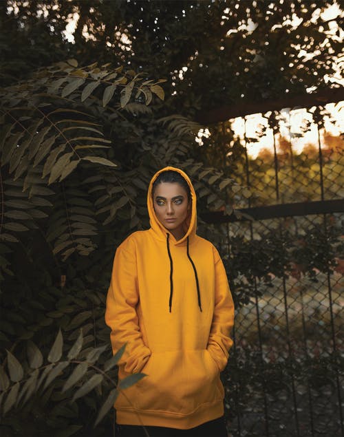 站在植物旁边的黄色连帽衫的女人 · 免费素材图片