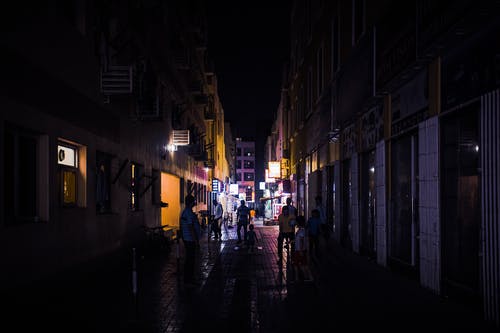 晚上在建筑物之间行走的人 · 免费素材图片