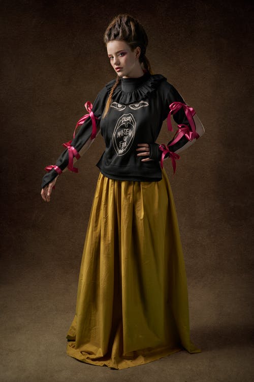 黑色上衣和棕色的连衣裙，摆在棕色背景前的女人的照片 · 免费素材图片